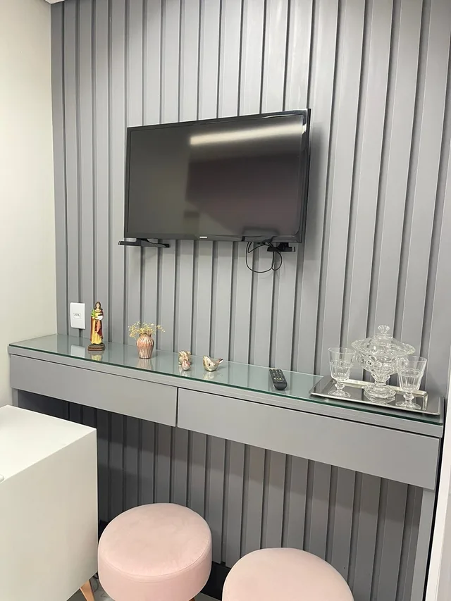 Bancada com objetos decorativos e banquetas rosa na espera